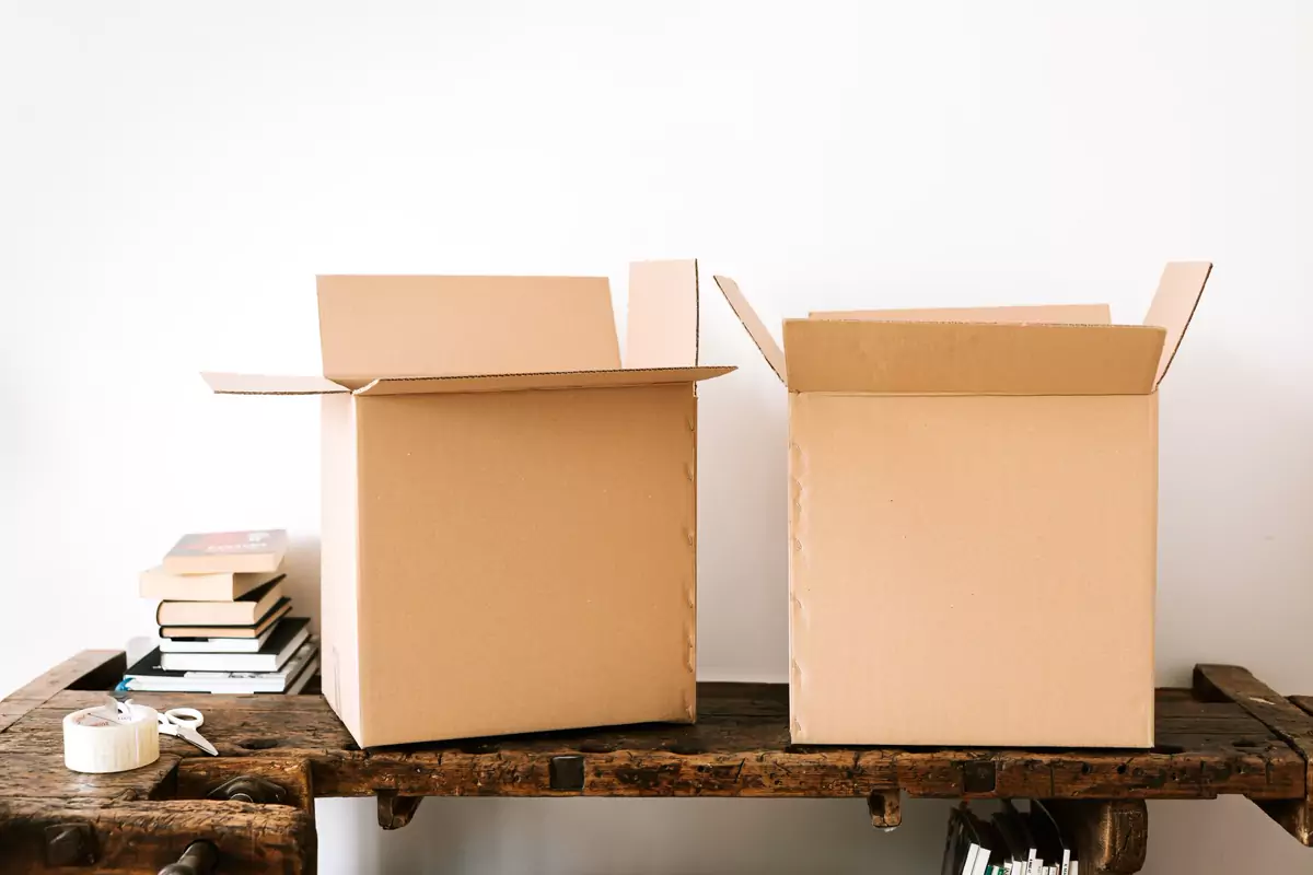 Bücher und offene Kartons stehen auf einem Schreibtisch zum Packen bereit