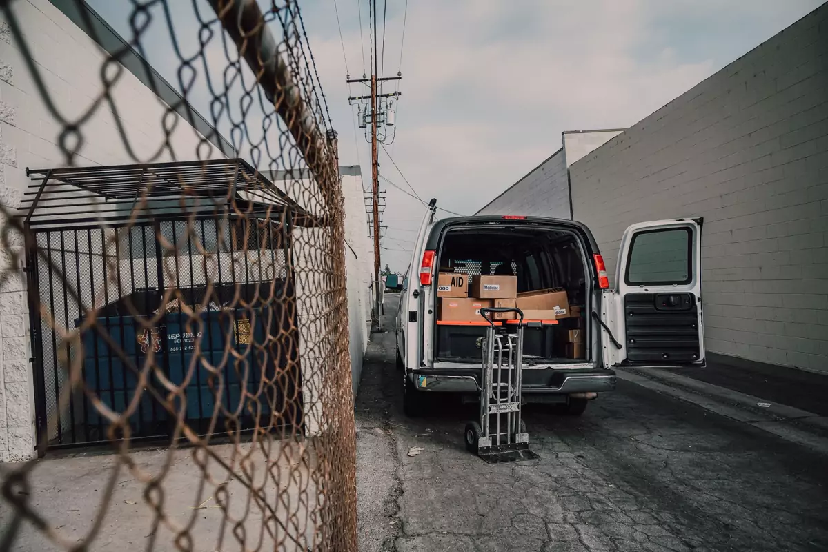 Ein offener Transporter mit Kartons steht in einer schmalen Zufahrt