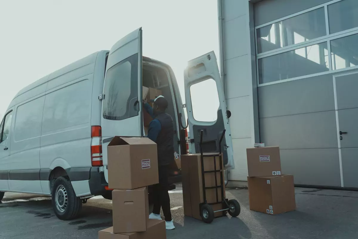 Kartons stehen zum Einladen neben einem offenen Transporter