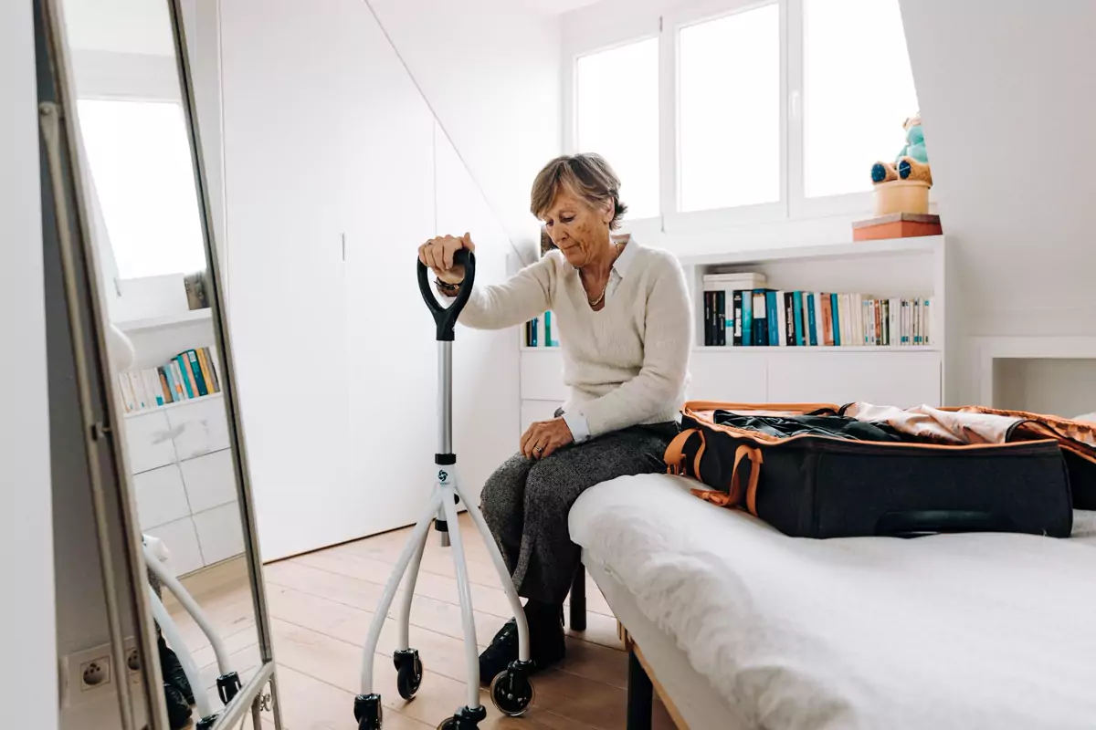 Eine Seniorin packt einen Koffer in einem hellen Schlafzimmer