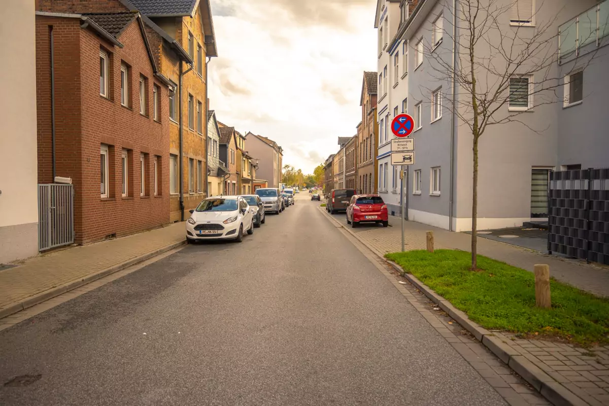 Eine Wohnstraße mit Mehrfamilienhäusern und herbstlichen Bäumen
