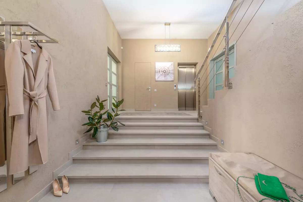 Ein heller Eingangsbereich mit Aufzug und breiter Treppe