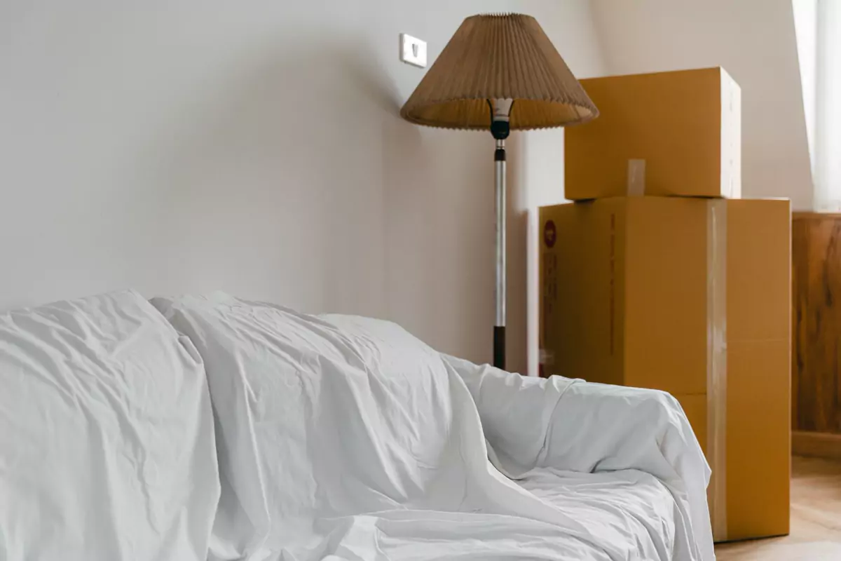 Abgedeckte Möbel und gepackte Kartons stehen in einem hellen Zimmer