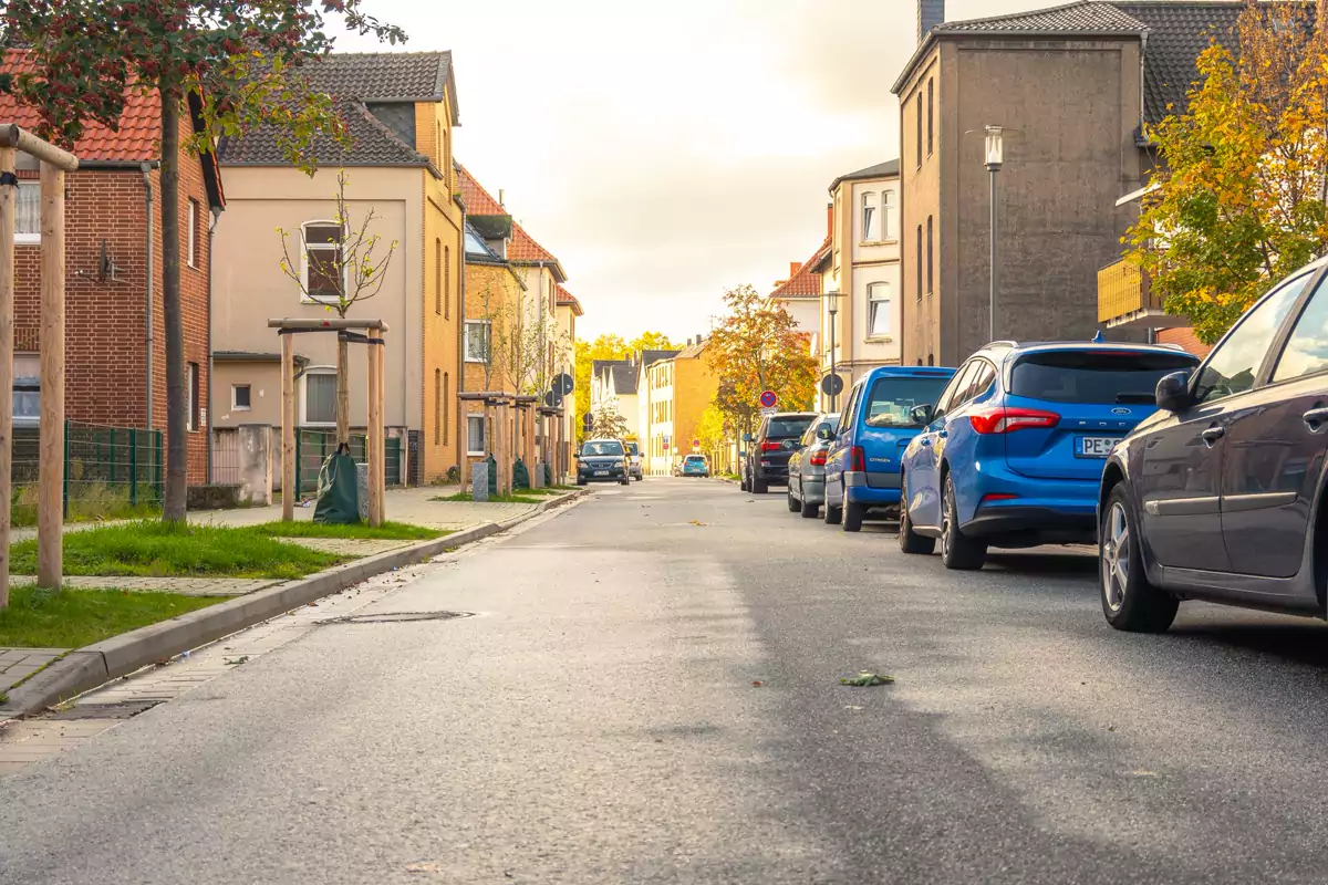 Eine Wohnstraße mit geparkten Autos und herbstlichen Bäumen