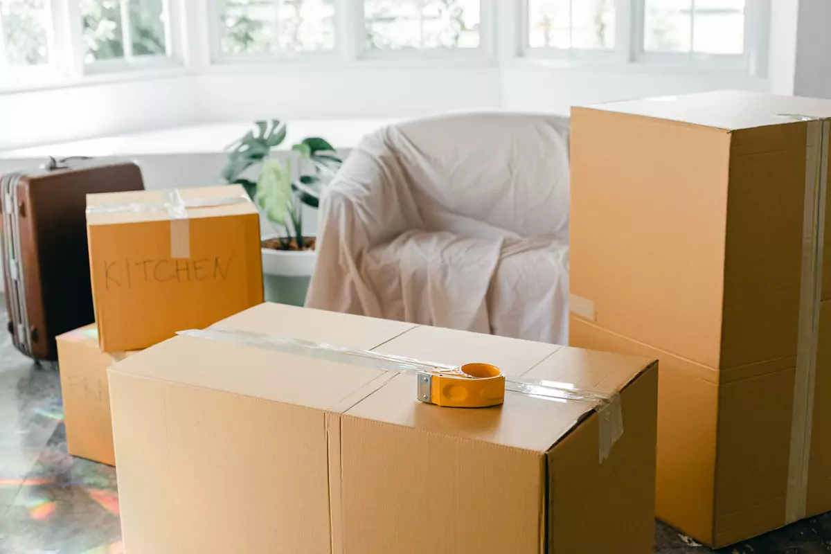 Gepackte Kartons und ein Koffer stehen in einem hellen Zimmer
